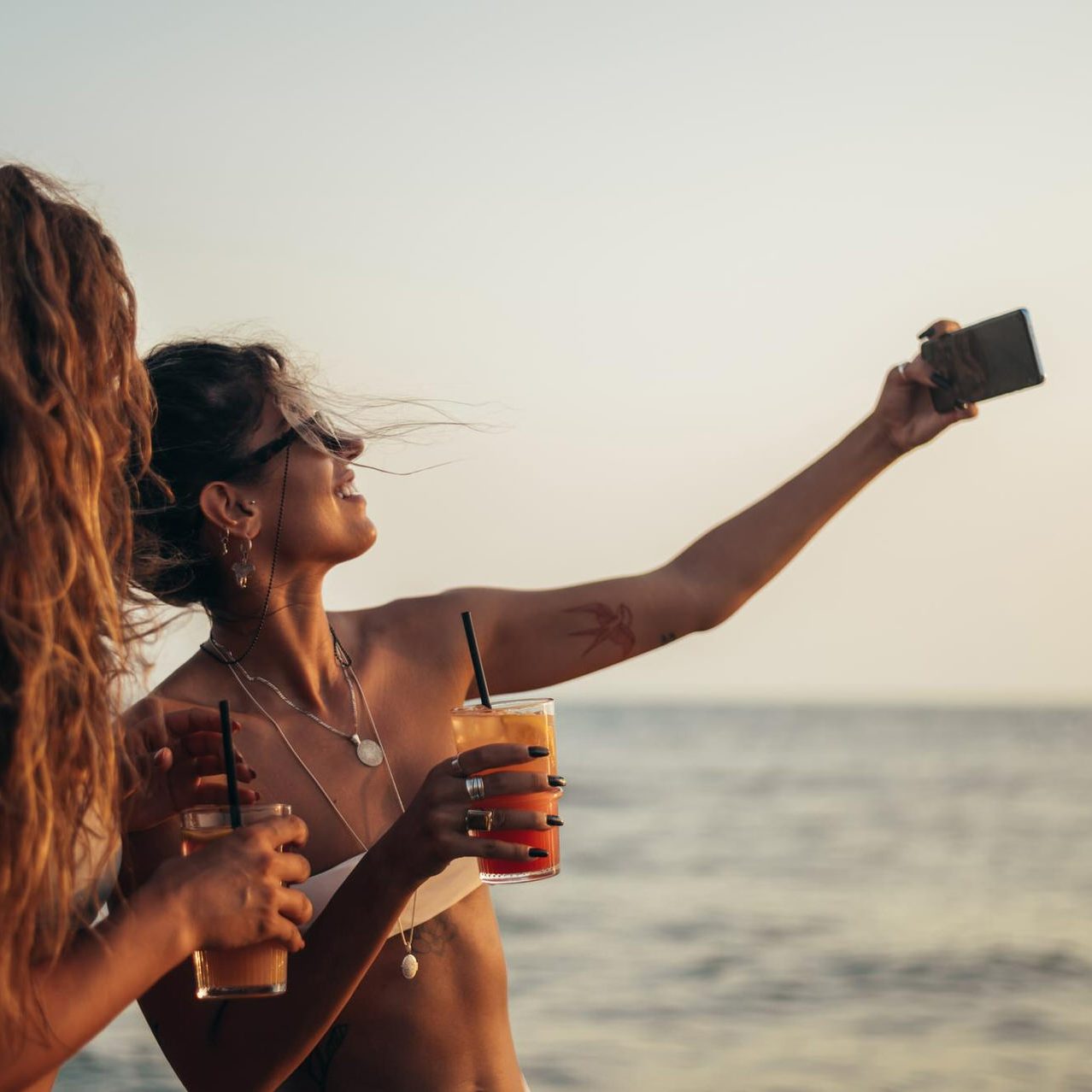 friends-enjoying-vacation-together-taking-selfie-beach-using-smartphone_1